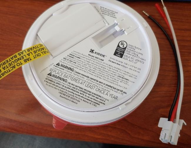 A picture of the back side of a smoke detector showing the new connection of a hard-wired detector.