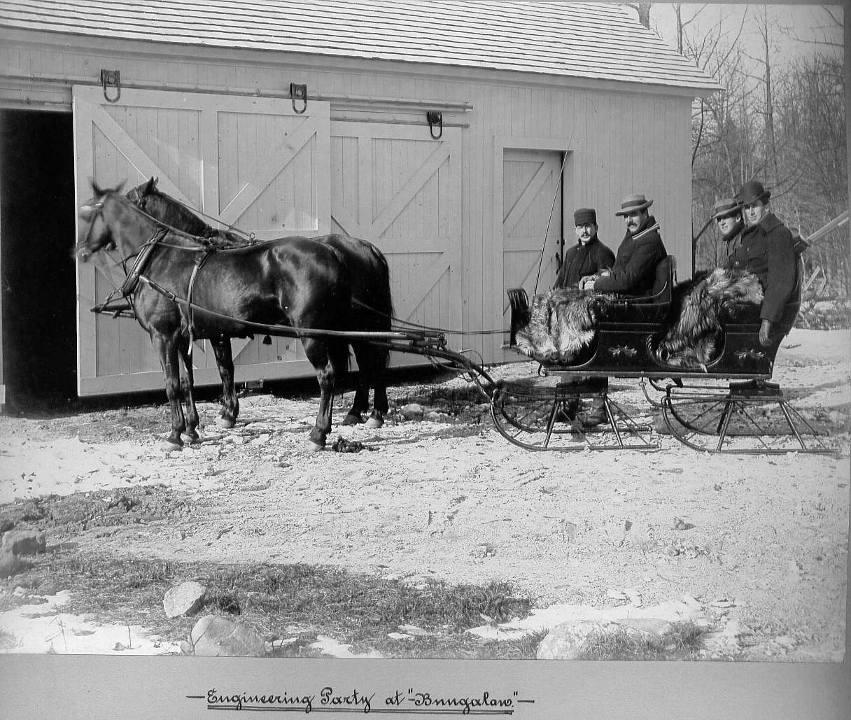 Men in horse drawn sleigh at barn